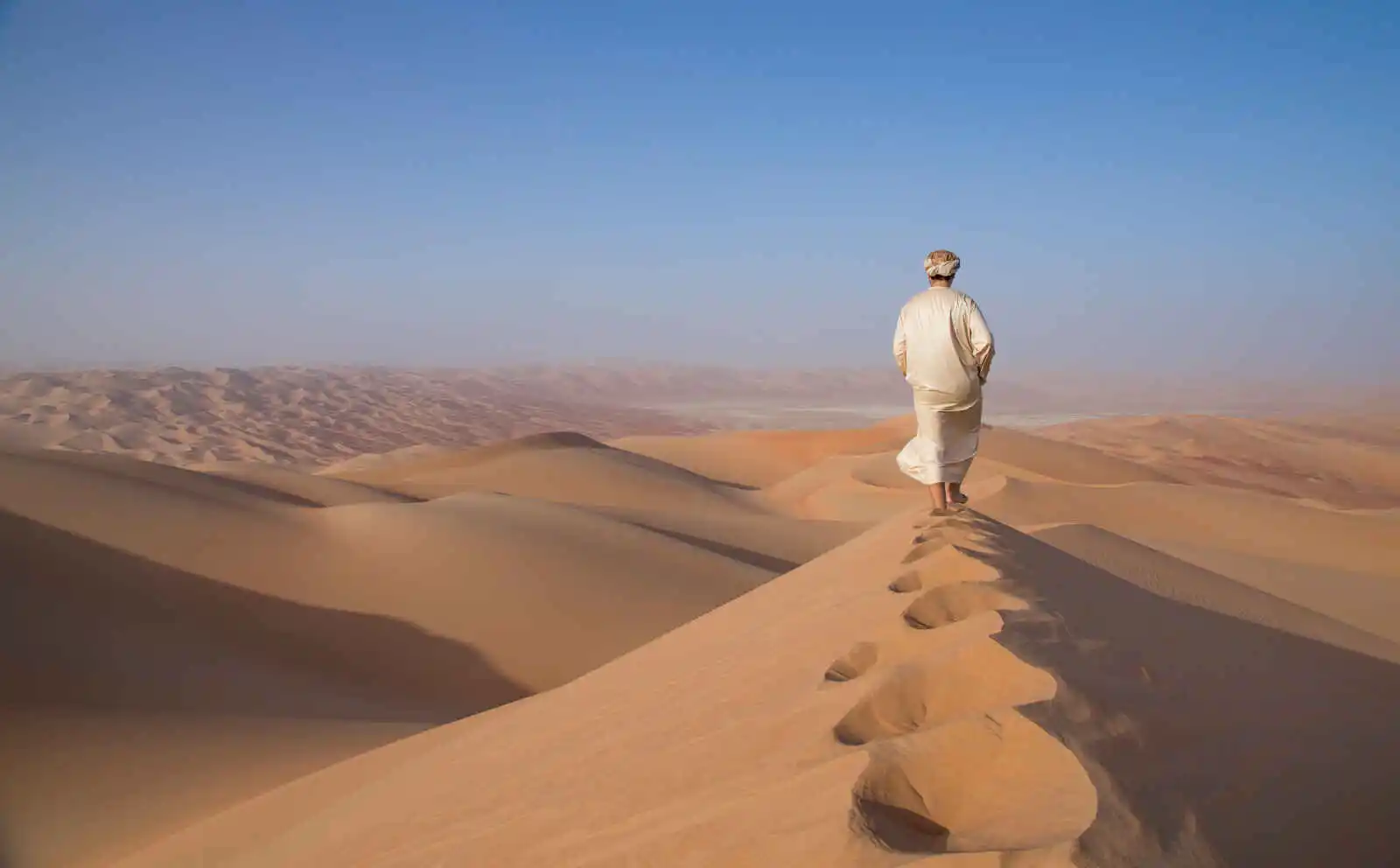 Homme en kandura (tunique arabe traditionnelle) dans le désert